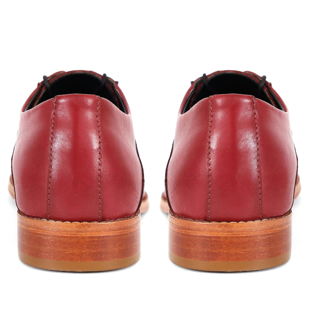 Red leather shoes with wooden soles on a white background