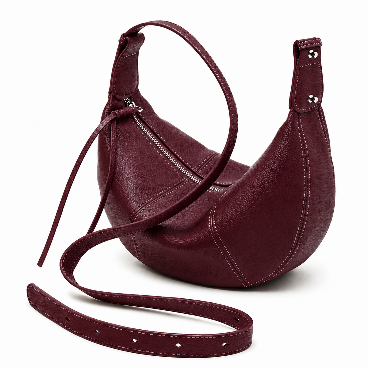 A crescent-shaped leather shoulder bag in deep burgundy, featuring a zippered main compartment, a long adjustable shoulder strap, and a detachable crossbody strap, shown on a white background.