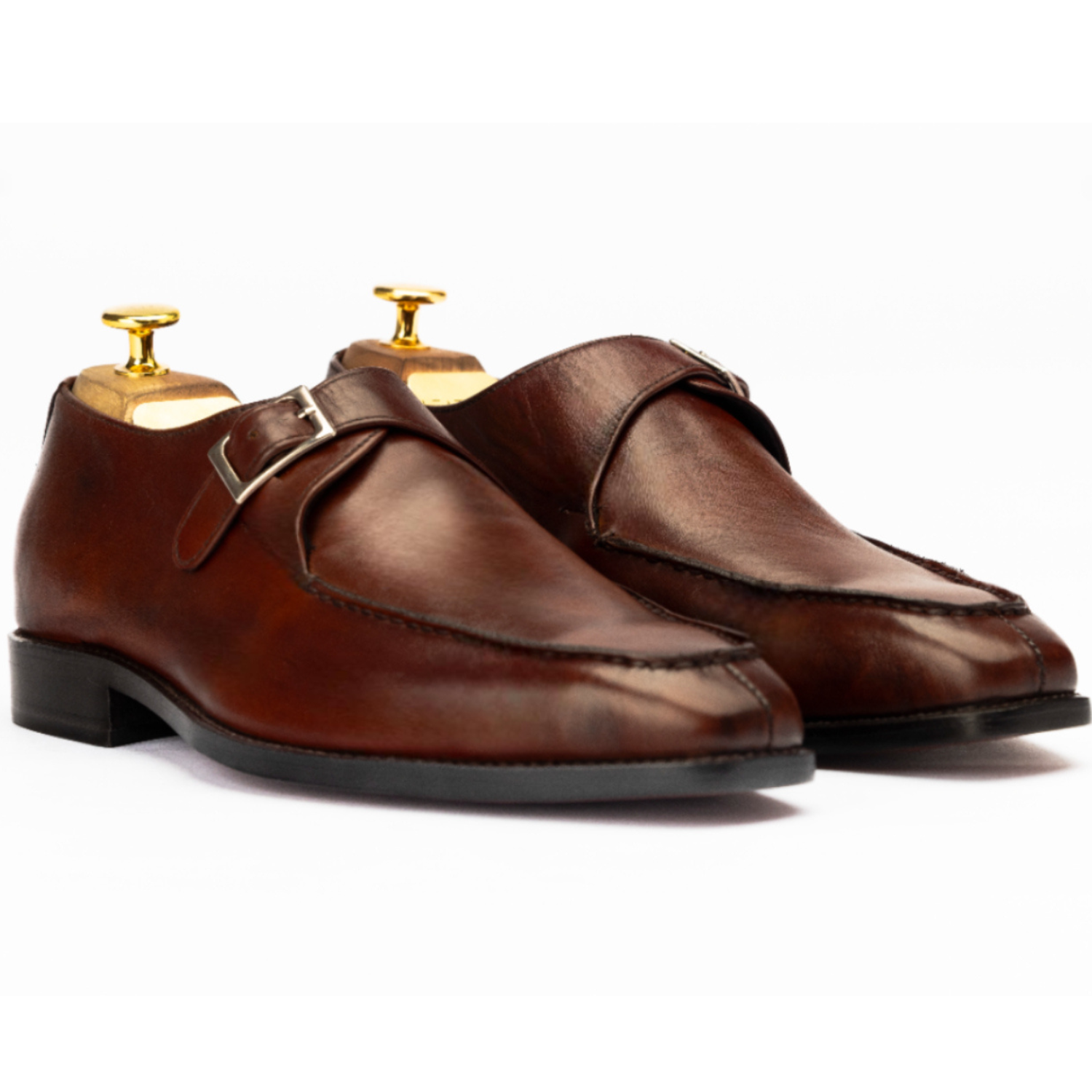 Pair of brown leather shoes with gold buckles on a white background