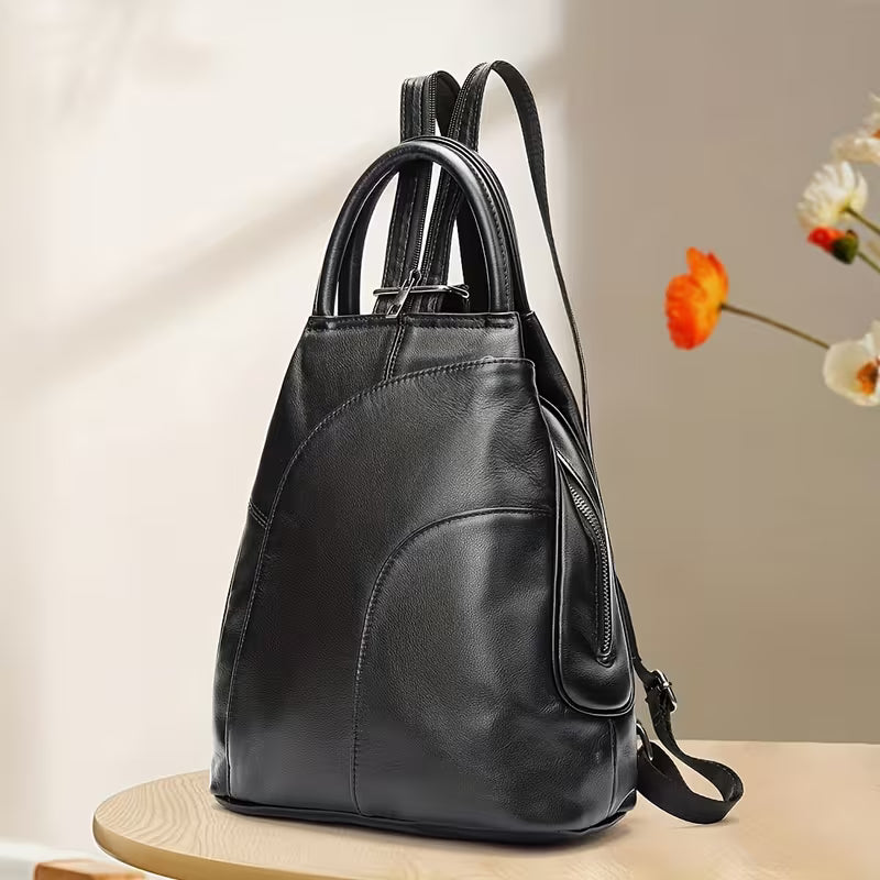Black leather backpack on a wooden surface with a blurred floral background