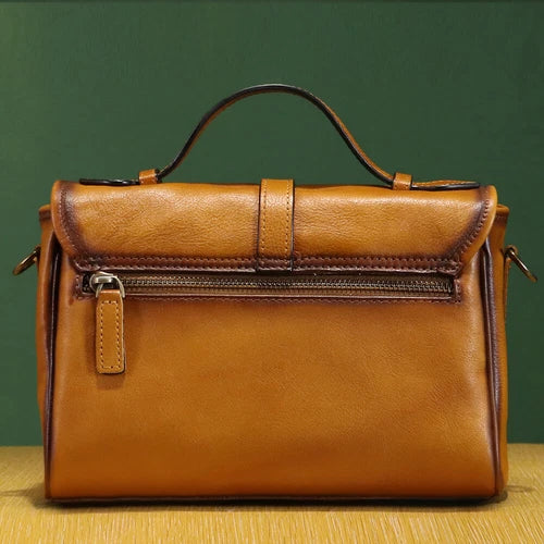 Brown leather handbag on a wooden surface with a green background